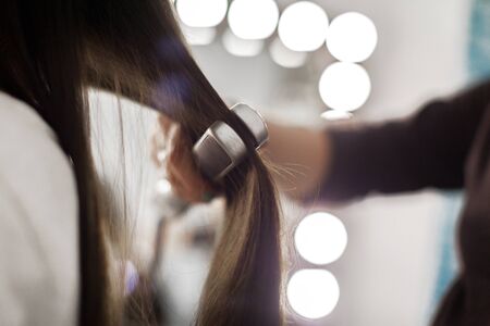 Hairdresser does hair style of womanの写真素材