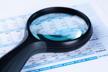 financial documents with magnifying glass over themの写真素材
