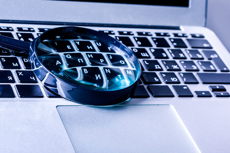 Closeup images of magnifying glass on laptop keyboardの写真素材