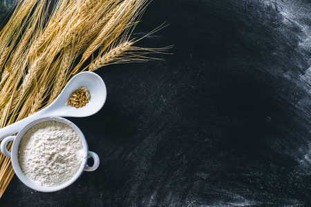 Wheat ears and flour on black backgroundの写真素材