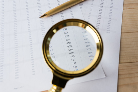 Looking through magnifying glass to financial reportの写真素材