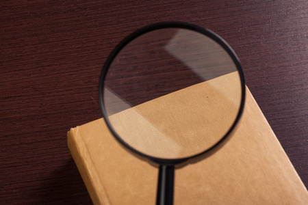 Magnifying glass and book o the wooden backgroundの写真素材