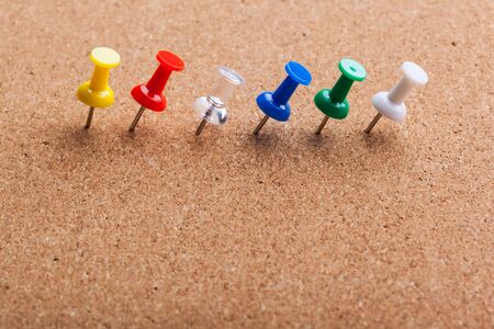 Group of thumbtacks pinned on corkboard