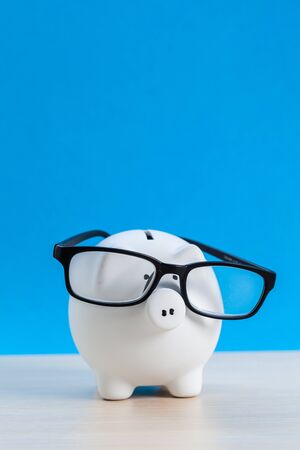 Piggy bank with glasses on blue backgroundの写真素材