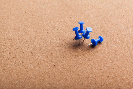 Group of thumbtacks pinned on corkboard