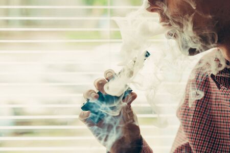 Close up on a man exhaling vapor from an electronic cigaretteの写真素材