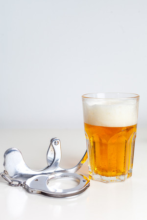Glass of beer with handcuffs as symbol for alcohol abuseの写真素材