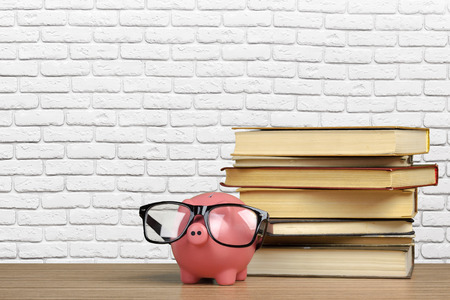 Piggy bank in glasses with booksの写真素材