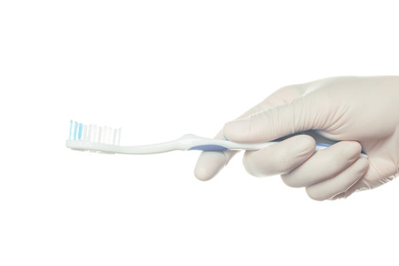 Gloved doctor's hand holding a toothbrush