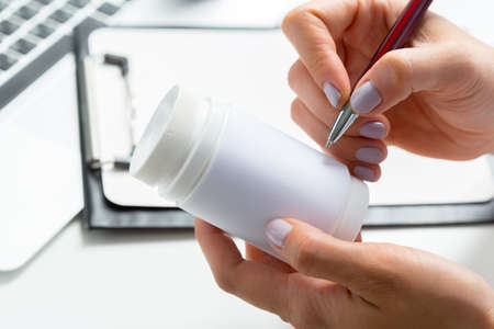 Female medicine doctor hands hold jar of pillsの写真素材