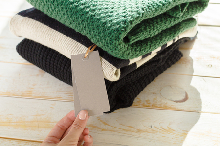 Stack of wool knitted warm sweater and white label for textの写真素材