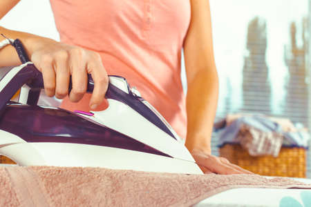 Closeup of woman ironing clothes on ironing boardの写真素材