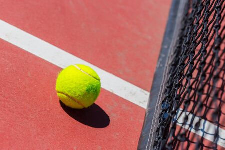 tennis ball on a tennis court with netの写真素材