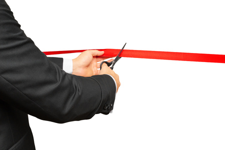 Scissors are cutting red ribbon or tape. Isolated on white background.の写真素材