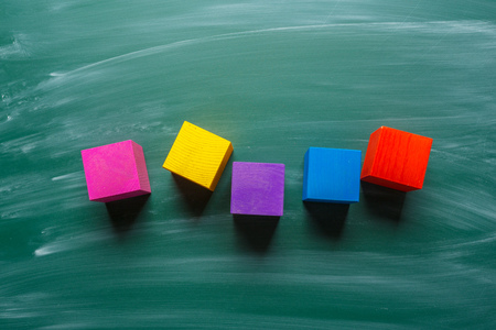colored wooden cubes on green chalkboardの写真素材