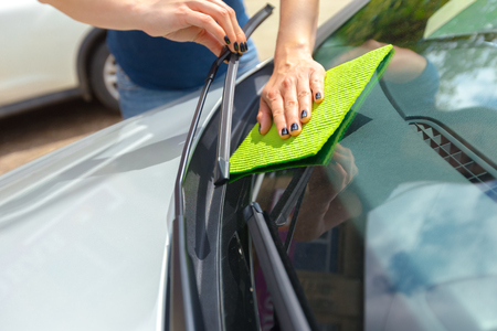 Hand with microfiber cloth cleaning car
