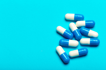 Pills are scattered over a blue background