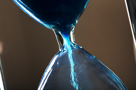 Time is passing. Blue hourglass close up