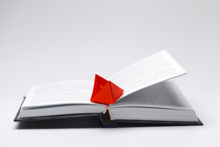 Origami paper boat on a bookの写真素材