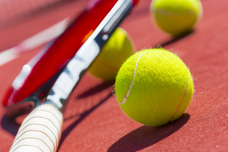 Tennis balls and racket on the grass courtの写真素材