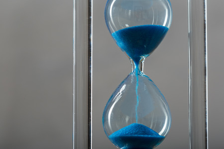 Time is passing. Blue hourglass close up