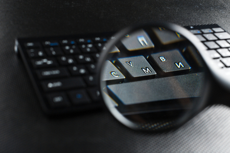Magnifying Glass on black keyboardの写真素材