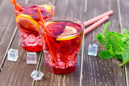 Summer drink with raspberries, lime and ice on a old wooden tableの写真素材