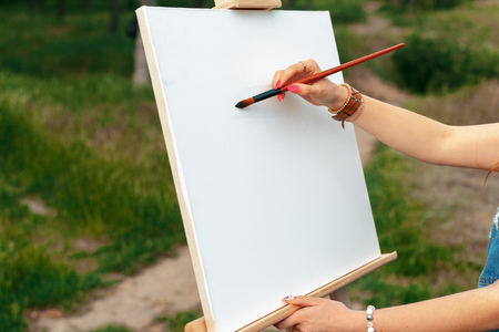 young caucasian woman painting on canvas outsideの写真素材