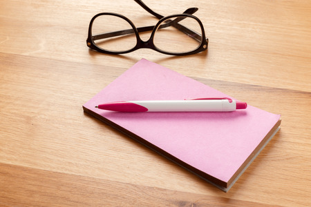 Notepad, pencil and glasses on the wooden backgroundの写真素材