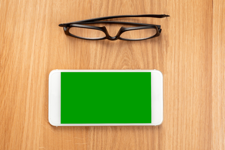glasses and smart phone on the wooden tableの写真素材