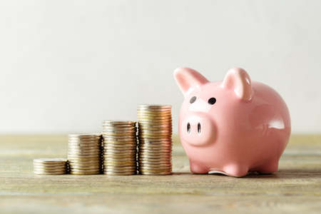piggy bank with coin on old wooden tableの写真素材