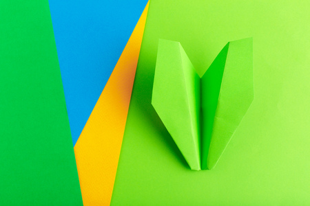 Flat lay of a paper plane on green pastel color backgroundの写真素材