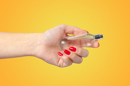 Woman hand holding a perfume bottle isolated on color backgroundの写真素材