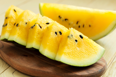 Yellow watermelon sliced on wooden backgroundの写真素材