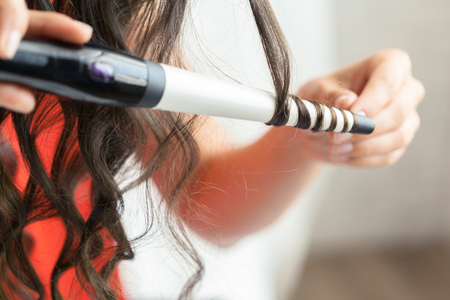 Hairstylist curling hair client in hairdressing salonの写真素材