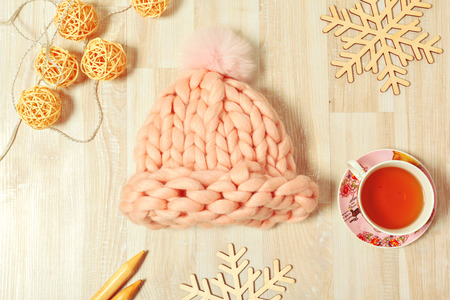 Handmade knitwear composition with warm hat of pastel color