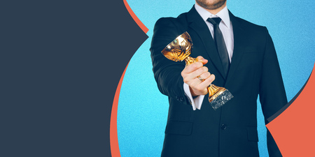 Unrecognizable businessman with a golden trophy. Success conceptの写真素材