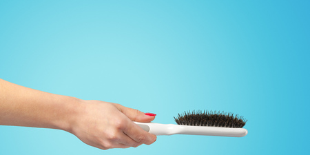 Woman hand with a hair comb isolated on a color backgroundの写真素材