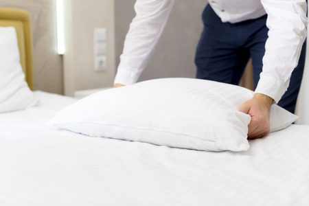 hotel staff setting up pillow on bedの写真素材