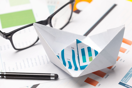 Boats made of paper graph on notebook with glasses and pen.Business Analysis concept.の写真素材