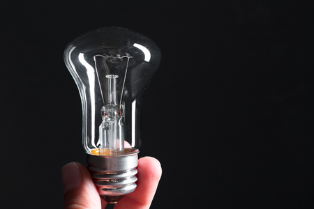 A classic Edison light bulb on dark background with space for text