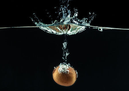 Splashing kiwi fruit on the waterの写真素材