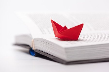 Origami paper boat on a bookの写真素材