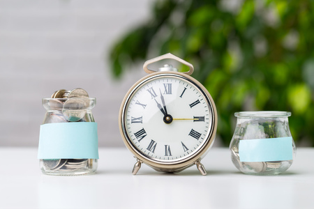 Coins in jar with alarm clock