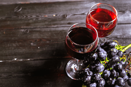 wine with branches of white grapes. On a wooden table.