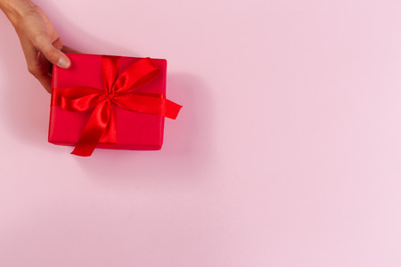 Woman holding gift box on color background