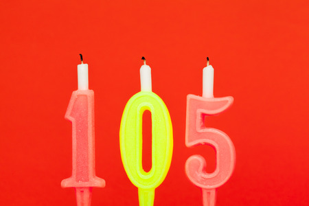 Colorful burning birthday candle  on red backgroundの写真素材