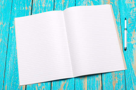 Top view workspace with blank notebook and pen on wooden table background
