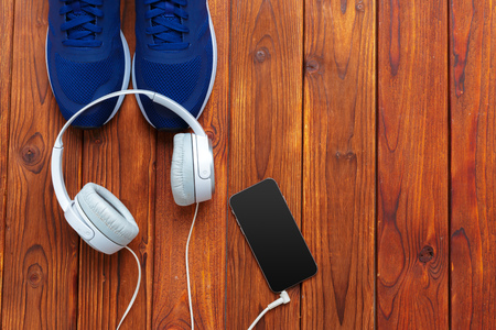Sneakers and mobile phone with headphones on wooden tableの写真素材