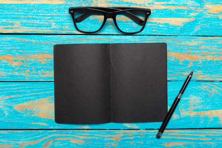 Top view workspace with blank notebook and pen on wooden table background